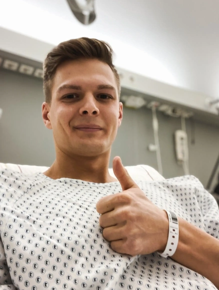 Ein optimistischer Johannes gibt mit erhobenem Daumen ein positives Zeichen direkt nach seiner Knochenmarkspende
