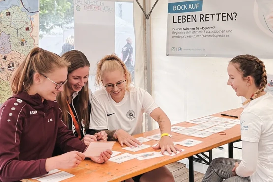 Die deutsche Frauenfußballmannschaft löst begeistert das Quiz über den Ablauf der Stammzellenspende. 