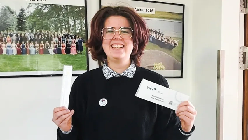 Lächelnde Schülerin Hannah steht stolz in den Fluren des Gymnasiums Hagenow, präsentiert die Registrierungskits und symbolisiert ihr Engagement für die Stammzellspende