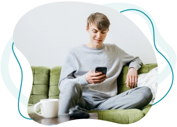Ein junger potenzieller Spender sitzt entspannt zu Hause auf der Couch und registriert sich online am Handy.