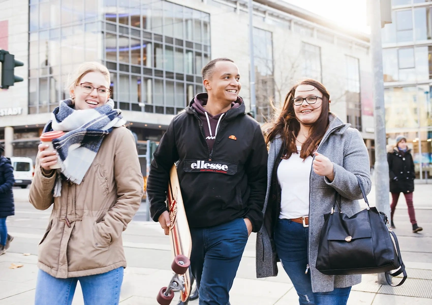 Drei junge Knochenmarkspender laufen lachend durch die Stadt, sie vereint das gemeinsame Erlebnis der Spende.