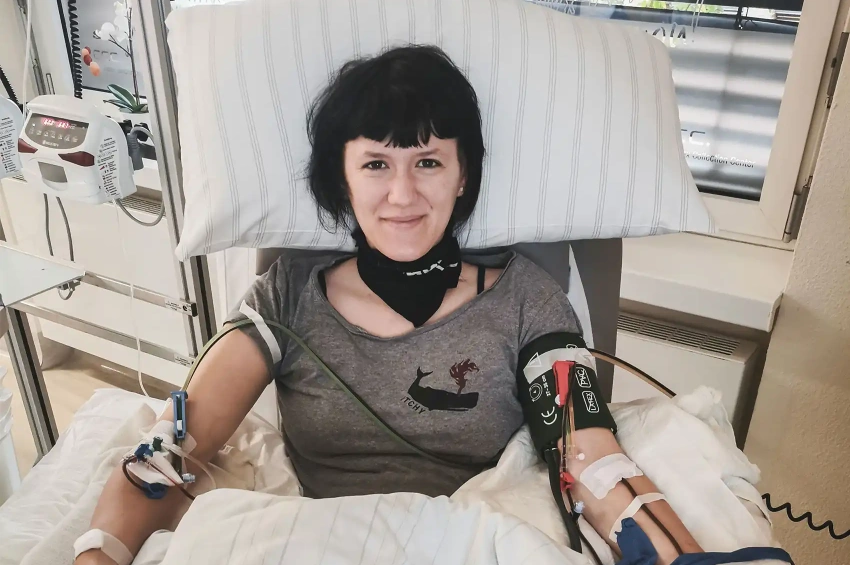 Stammzellspenderin Pauline bei der peripheren Stammzellspende. Sie freut sich, da sie weiß, dass sie ihrem genetischer Zwilling eine Chance auf Heilung schenkt.