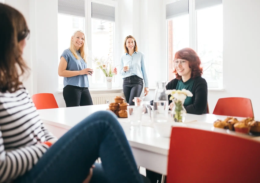 Das VKS Team sitzt zusammen in der Küche und unterhält sich über aktuelle Themen. Dabei freuen sie sich über die guten Neuigkeiten und über die Muffins.