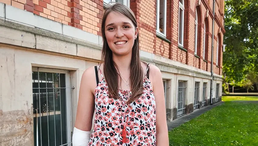 Annika ist eine Stammzellspenderin und posiert vor dem VKS Büro in Dresden. Sie wirkt sehr glücklich. 