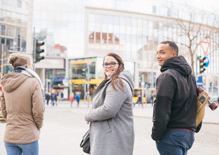 Drei junge Knochenmarkspender laufen gemeinsam durch die Stadt. Zwei Spender schauen dabei zurück und strahlen. 