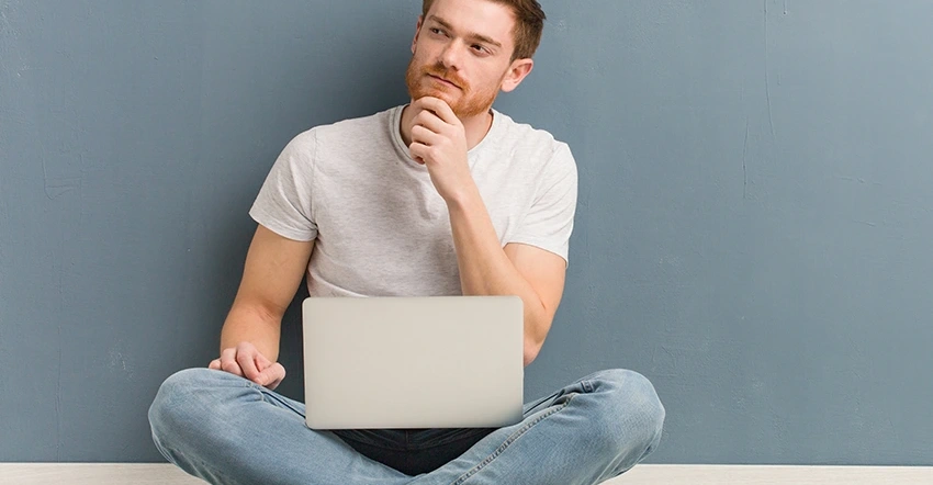 Ein junger potenzieller Spender sitzt entspannt zu Hause mit dem Laptop auf dem Schoss und schaut fragend. Er überlegt: Was ist eigentlich Blutkrebs.