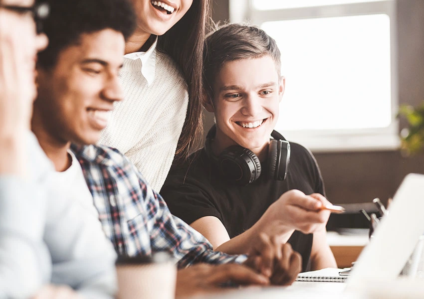 Schüler und Schülerinnen sitzen gut gelaunt beim Schul-Workshop über Blutkrebs an einem Tisch und erarbeiten gemeinsam Informationen zum Thema Blutkrebs.